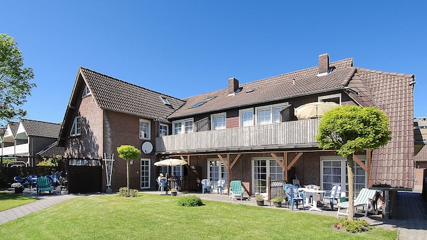 Een gebouw met twee verdiepingen, een balkon, een terras en een verzorgd gazon.