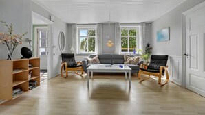 A spacious living room with a sofa, two rocking chairs, a coffee table, and a bookshelf. - Awesome home in Nexø with sauna (Nexø)