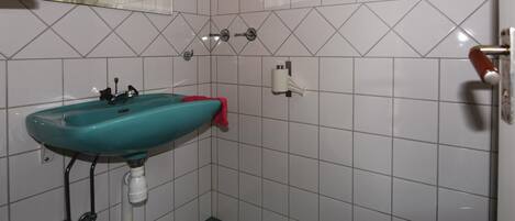 A bathroom with a turquoise sink, white tiles, a toilet, and a mirror.