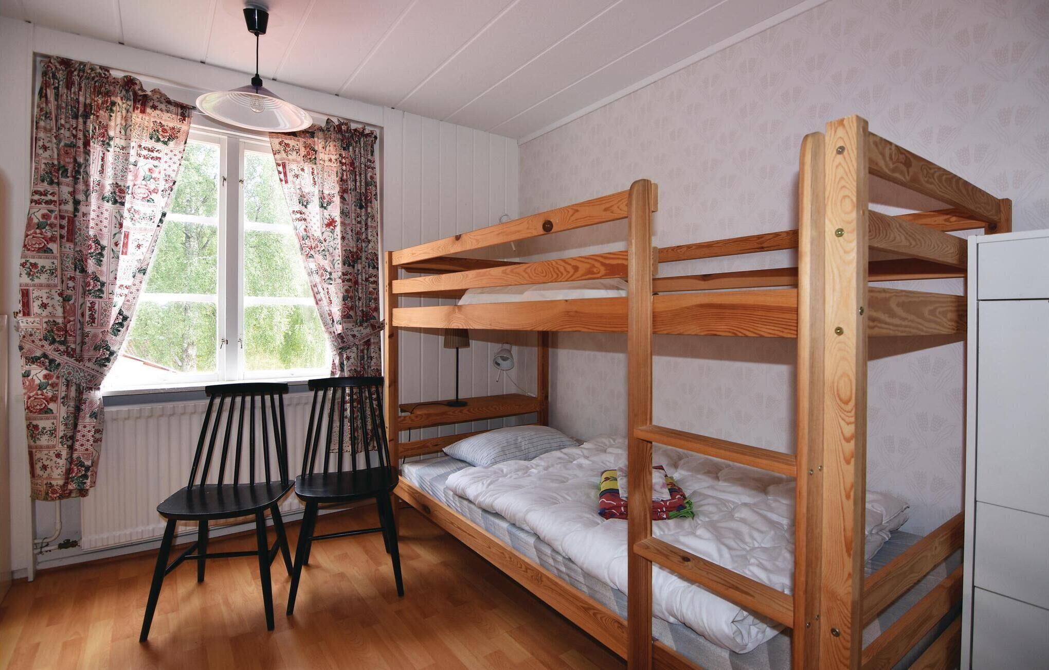 A bunk bed room with a window, two chairs, and a radiator.