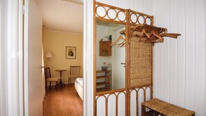 A room with a wooden floor, a bed, a chair, a small table, and a mirror with a woven frame. - 3 bEdroom pet friendly home in Ed (Ed)