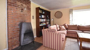 A cozy living room with a brick fireplace, a striped sofa, a wooden bookshelf, and a round woven wall hanging. - 3 bEdroom pet friendly home in Ed (Ed)