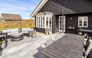 En terrasse med udendørs møbler, grill og en veranda med vinduer.