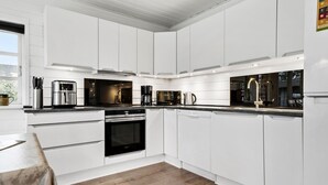 A modern kitchen with white cabinetry, stainless steel appliances, and a wooden floor. - Amazing home in Tarm with sauna (Tarm)