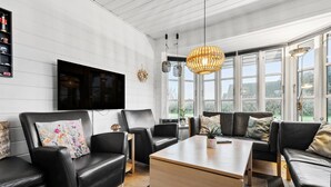 A modern living room with black leather sofas, a wooden coffee table, and a large TV mounted on the wall. - Amazing home in Tarm with sauna (Tarm)