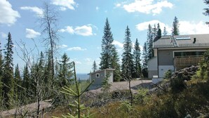 A modern two-story house with a balcony, surrounded by tall evergreen trees and a clear sky. - 5 bedroom gorgeous home in Sälen (Sälen)