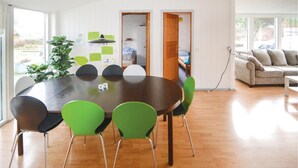 Uma sala de jantar moderna com uma mesa redonda, cadeiras verdes e piso de madeira.