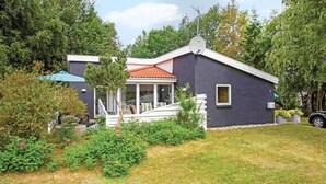Uma casa moderna com varanda coberta, antena parabólica e um jardim bem cuidado.