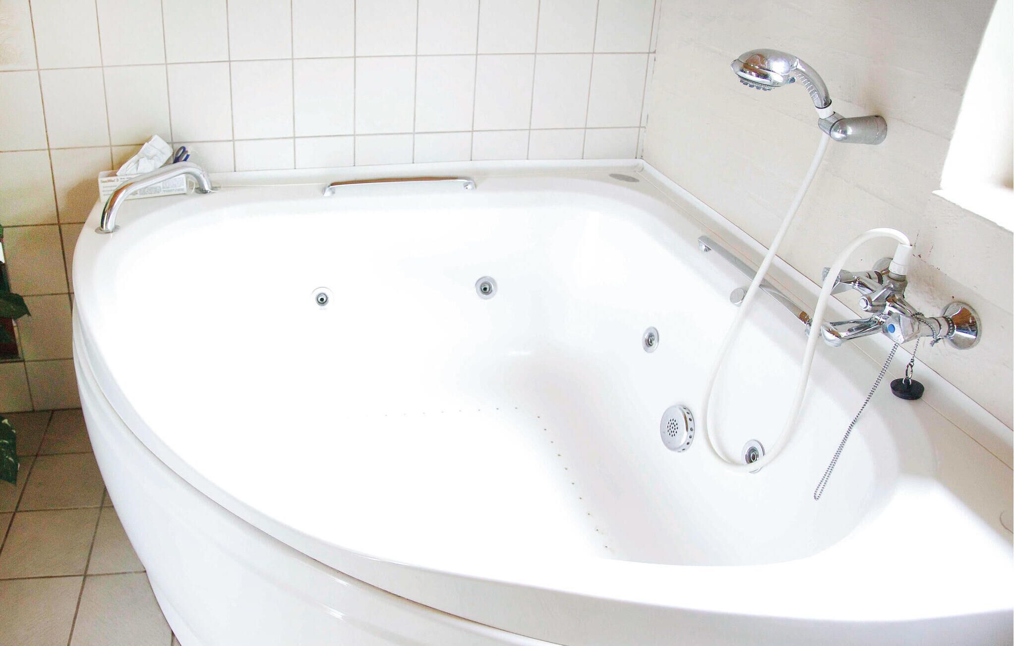A white bathtub with a handheld showerhead and a built-in faucet.