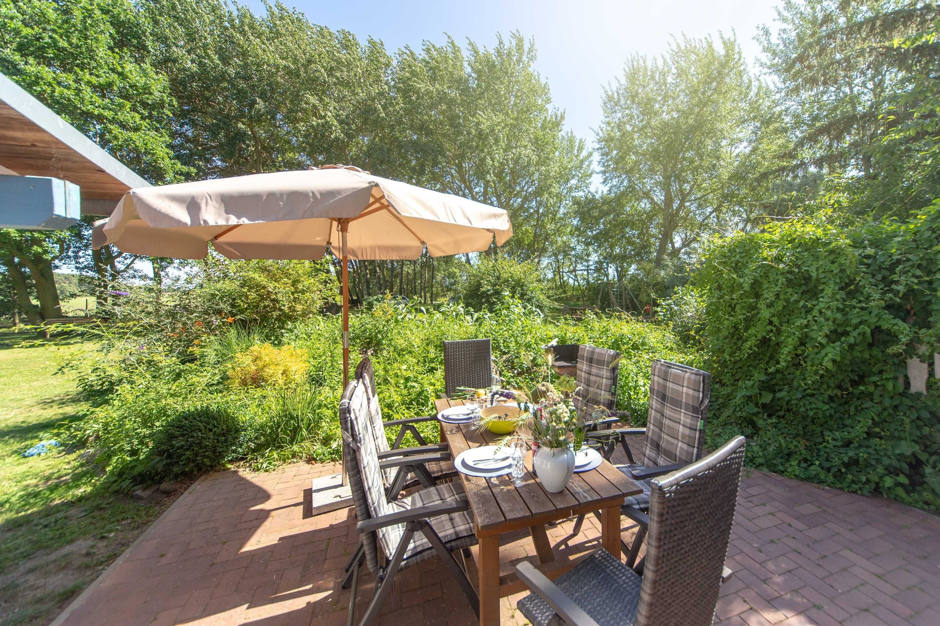 Une terrasse extérieure avec une table, des chaises et un parasol.