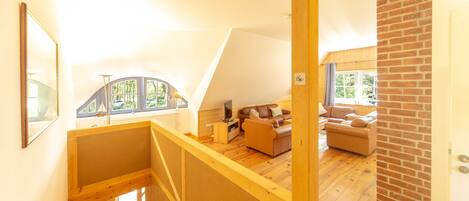 A loft-style room with a wooden staircase, a sofa, a coffee table, and a view of the outdoors.