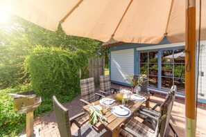 A patio with a table set for four, surrounded by wicker chairs, under a large canopy.