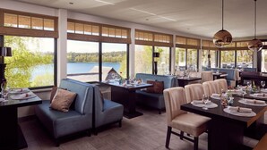 A restaurant with a lakeside view, featuring a mix of seating including a booth and a table with chairs.