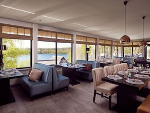A restaurant with a lakeside view, featuring a mix of seating including a booth and a table with chairs. - 45m² holiday home half - holiday houses at the lake (Nossentiner Hütte)