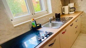 Et køkken med sort bordplade, vask, mikroovn og kaffemaskine.