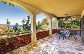 Enjoy a tranquil outdoor space with a view of the sea, featuring a table and chairs amidst lush surroundings.