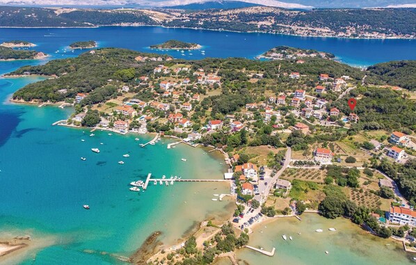 Overlooking a bustling marina with docks and moored boats, this coastal town offers scenic views of lush hills and open spaces.