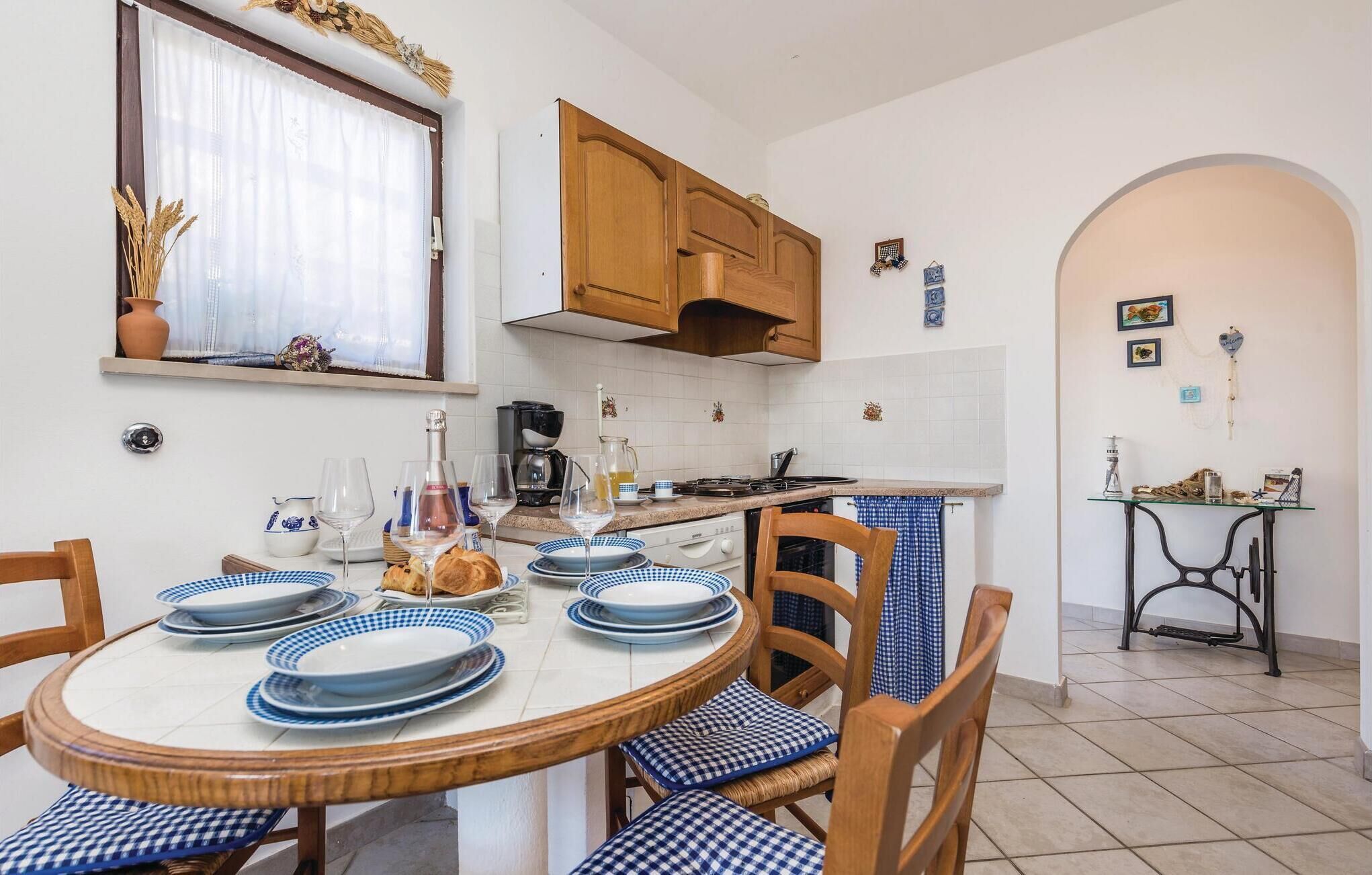 Una cucina con un tavolo rotondo apparecchiato per mangiare, pensili in legno e uno schienale piastrellato.