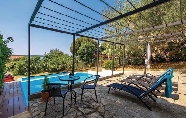 A covered outdoor area with a pool, lounge chairs, and a table. - Gorgeous apartment in Supetarska Draga (Supetarska Draga)