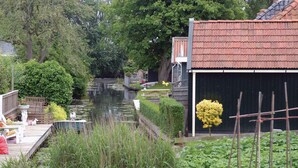 Una propiedad junto a un canal, con un muelle de madera, un cobertizo pequeño y abundante vegetación.