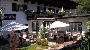 Un edificio con mesas al aire libre, un cartel que dice 'Landhaus St. Georg' y un balcón con macetas.