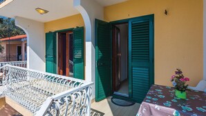 A balcony with a white railing, a table with a floral tablecloth, and green shutters on the doors. - 2 bedroom gorgeous apartment in Rogoznica (Rogoznica)