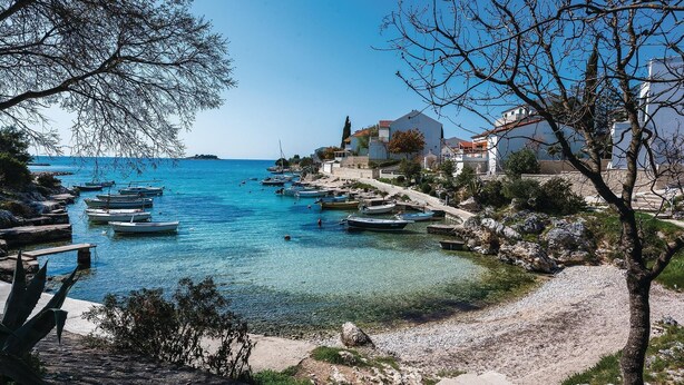 A coastal scene with clear blue waters, boats docked along the shore, and buildings with balconies overlooking the sea. - 2 bedroom gorgeous apartment in Rogoznica (Rogoznica)