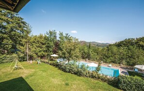 Un jardin avec une piscine, une balançoire et une vue sur une zone boisée.