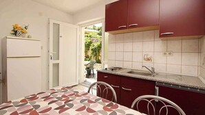 A compact kitchen with a dining table, a refrigerator, and a sink. - Holiday apartment mit Klimaanlage und Terrasse (Šilo)