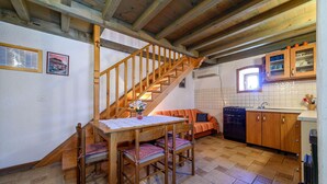 A cozy kitchen with a wooden staircase, a dining table with chairs, and a kitchen counter with cabinets. - 1 bedroom awesome home in Jadrija (Jadrija)