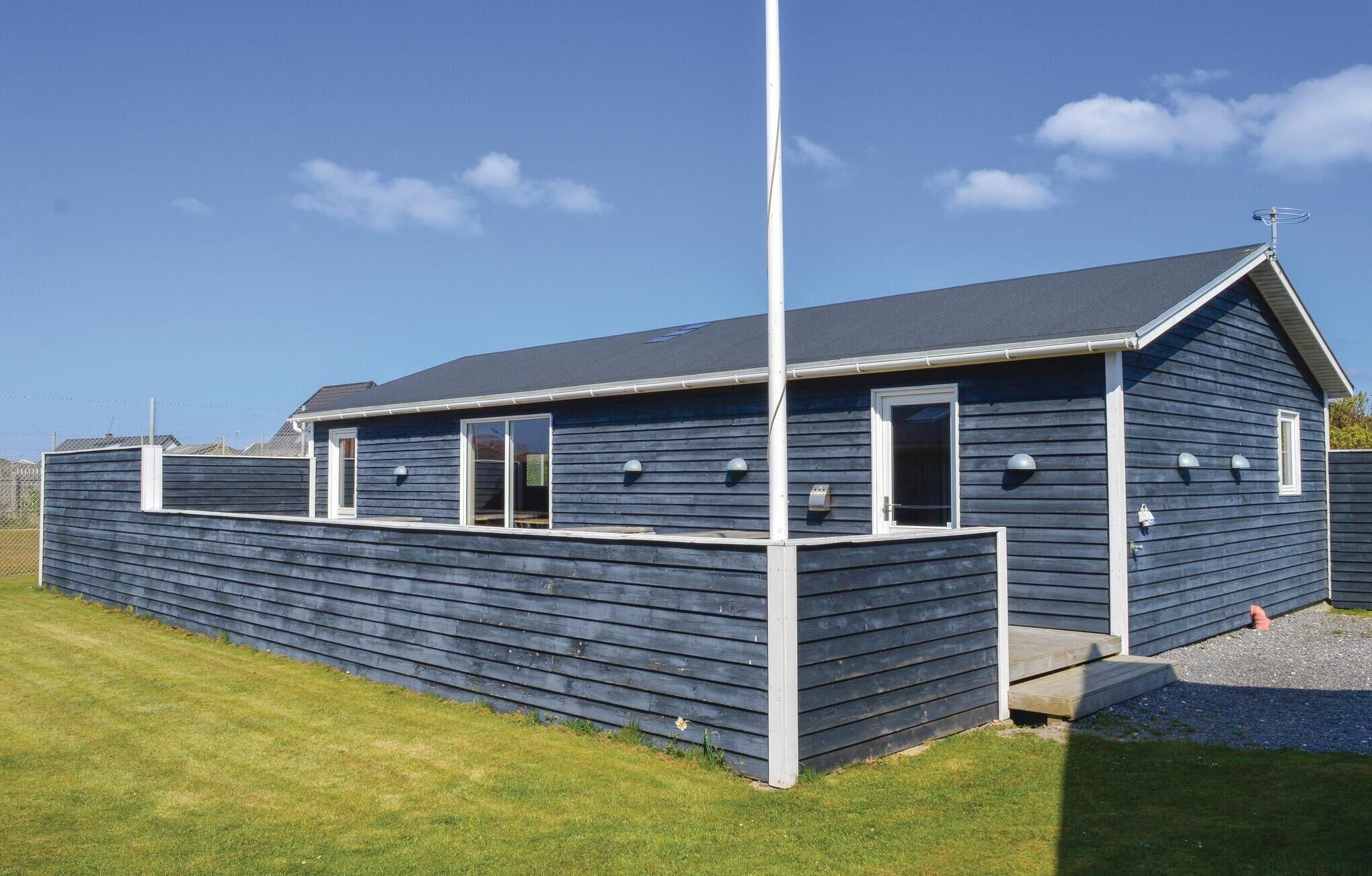 Een laag gebouw met een donkerblauwe gevel, een witte deur en een klein portaaltje met treden.