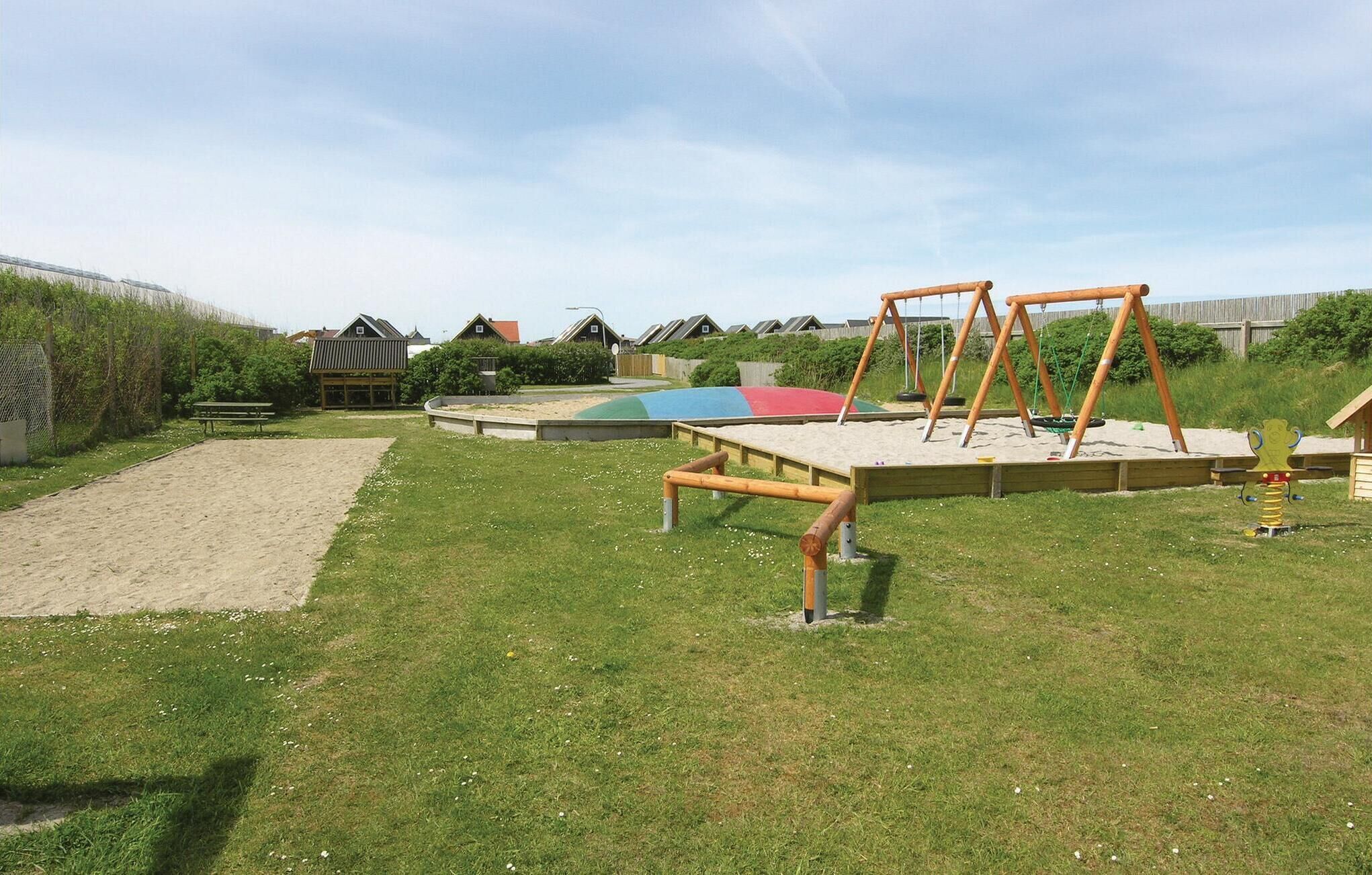Une aire de jeux avec des balançoires, un toboggan et un bac à sable.
