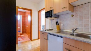 A kitchen with wooden cabinets, a stainless steel sink, and a microwave.