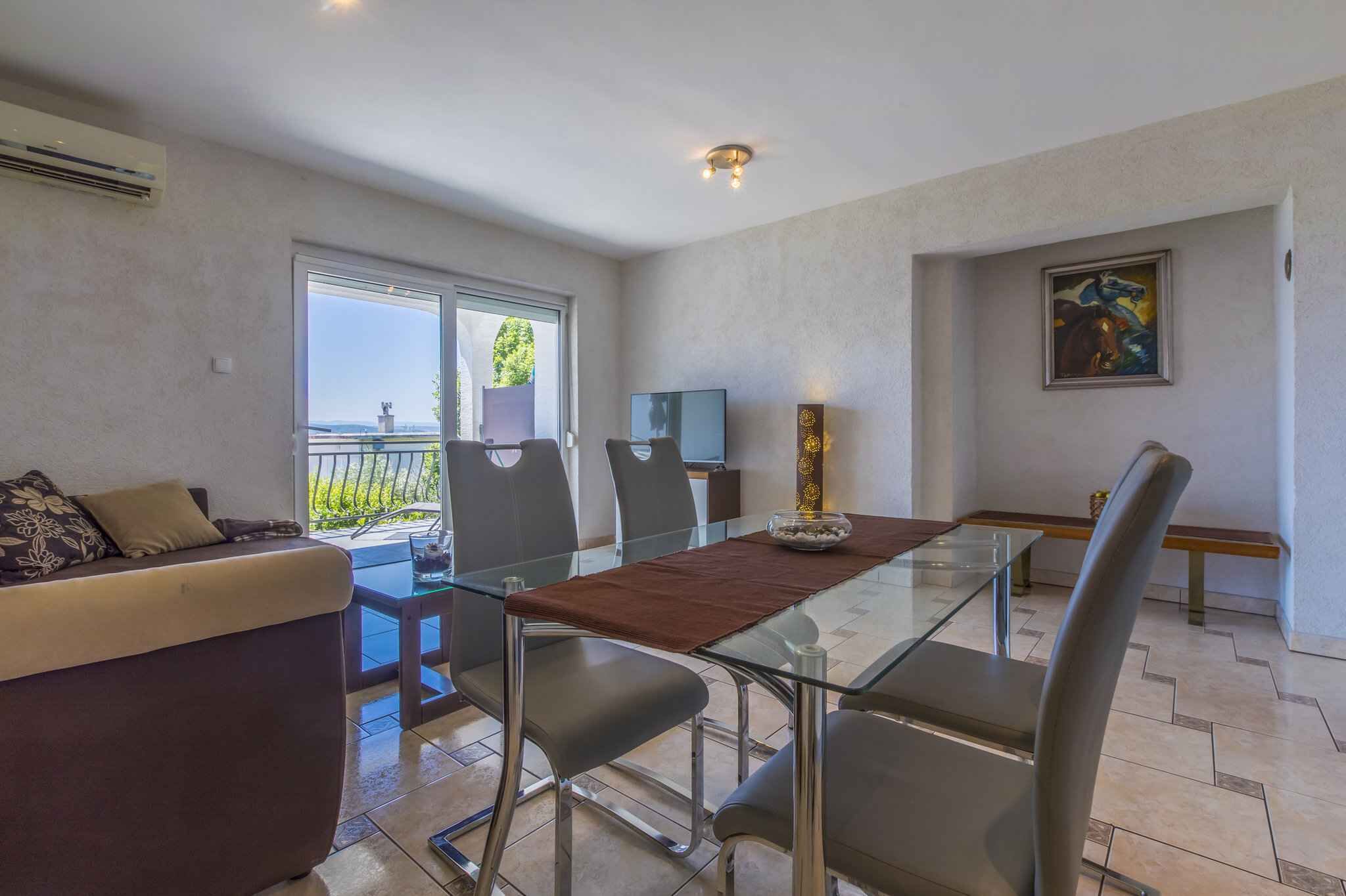 Un comedor moderno con una mesa de vidrio, sillas de metal y un mantel individual marrón.