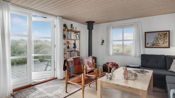 En hyggelig stue med pejs, reol, sofa og spiseplads.