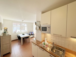 A modern kitchen with a built-in microwave, a wooden countertop, and a stainless steel sink.
