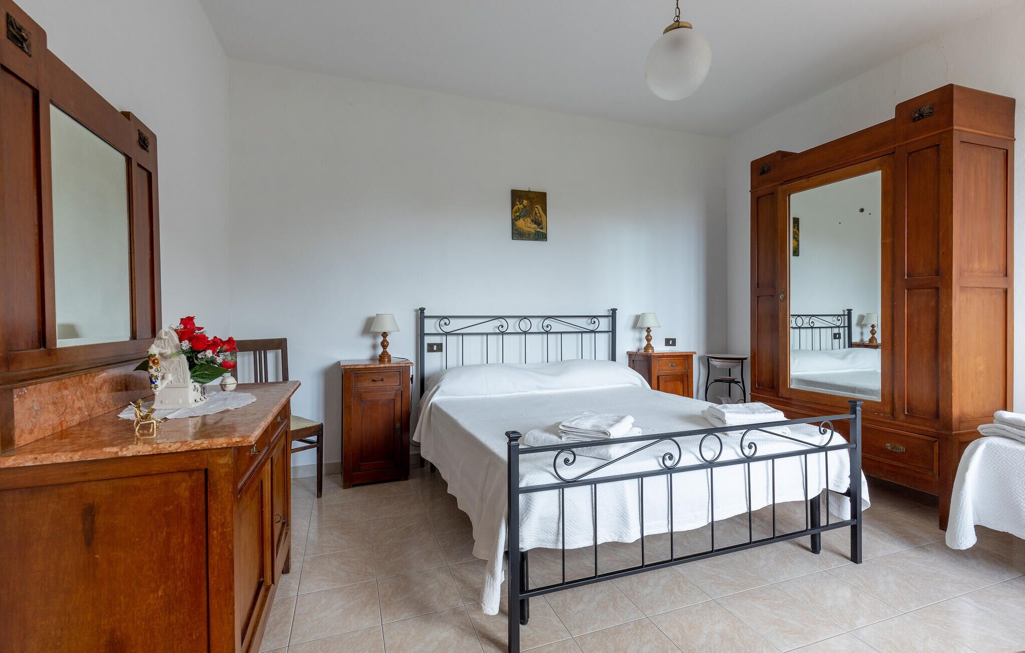 Une chambre à coucher avec un lit, une commode en bois et un grand miroir.