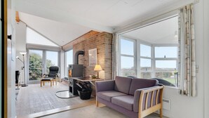 A modern living room with a fireplace, a sofa, and a dining area. - 2 bedroom lovely home in Slagelse (Slagelse)