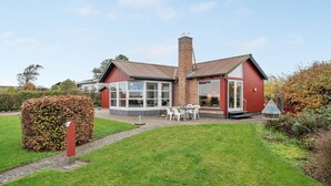 A red brick house with a large glass window, a chimney, and a small garden with a white chair and table. - 2 bedroom lovely home in Slagelse (Slagelse)