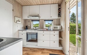 Enjoy cooking and preparing meals in this well-lit kitchen with a stove, microwave, and kettle.