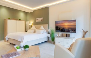 Une chambre à coucher moderne, équipée d’un lit, de tables de chevet, d’une télévision et offrant une vue sur le coucher de soleil.
