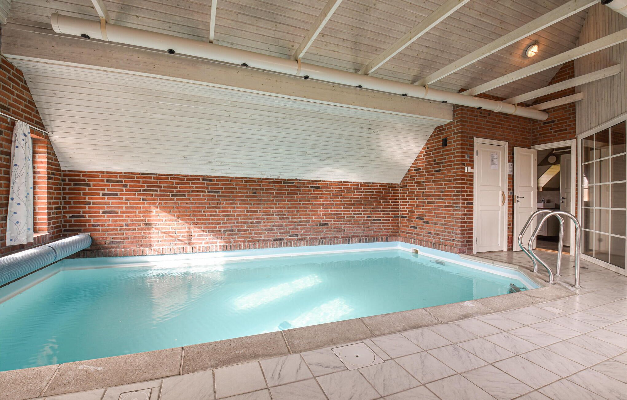 An indoor swimming pool with a brick wall and tiled floor.