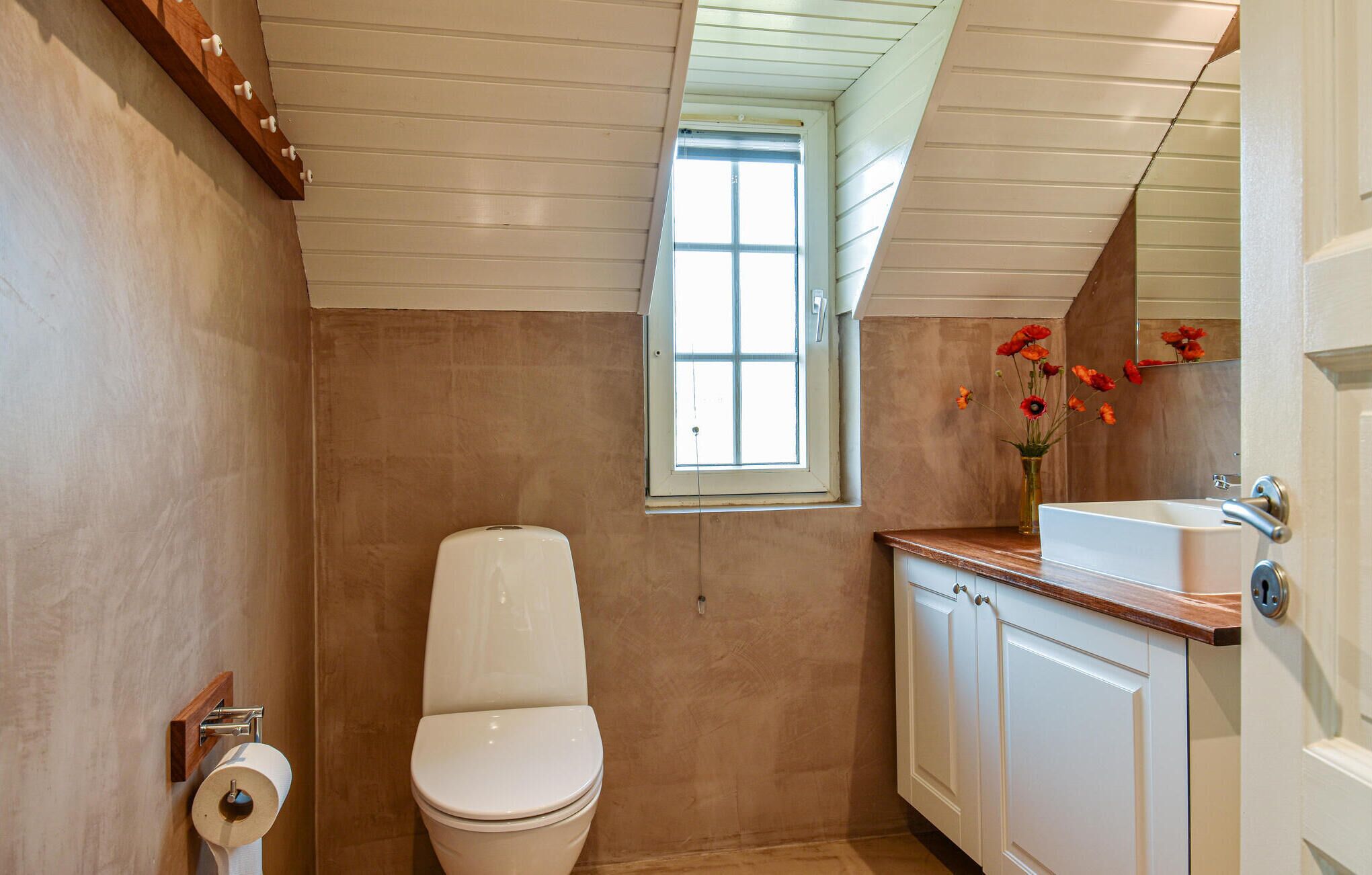 Ein Badezimmer mit Toilette, Fenster, Waschbecken und Schrank.