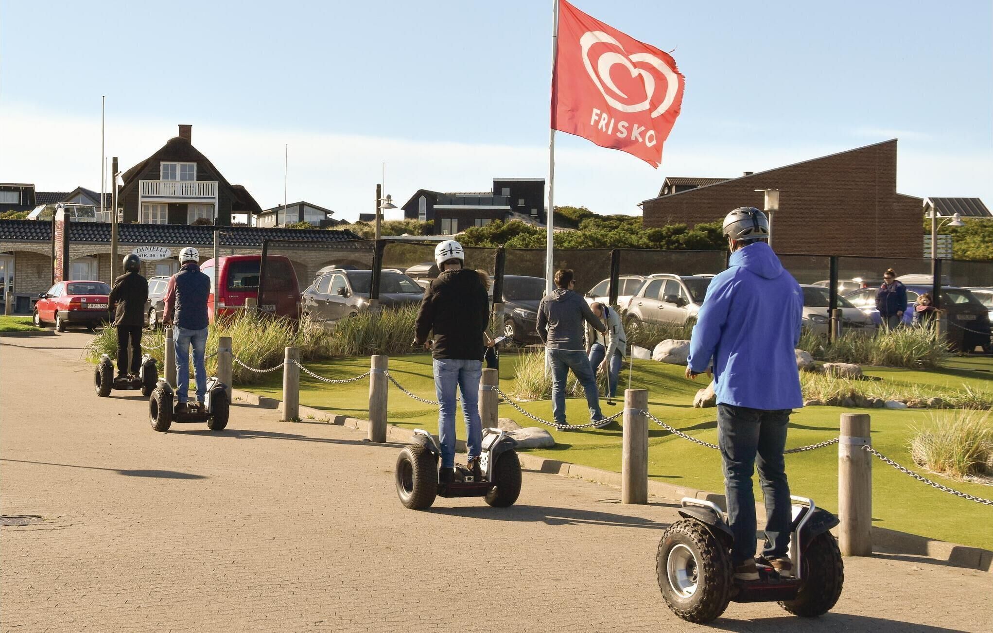 Personas montando Segways por un sendero pavimentado, con una bandera roja al fondo.
