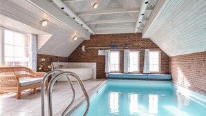 Une piscine avec un plafond en bois, un canapé en osier et une baignoire.