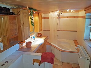 Ein Badezimmer mit einem Holzkosmetikschrank, einem weißen Waschbecken, einer Badewanne und einer Dusche.