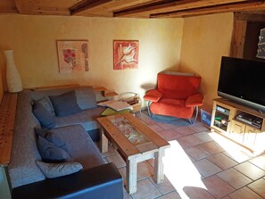 Una sala de estar acogedora con sofá, sillón y mueble para televisión.