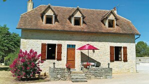 A stone house with a tiled roof, two chimneys, and a red umbrella. - Gorgeous home in Padirac (Padirac)