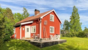 A red wooden house with a porch, a chimney, and a small deck with chairs. - Amazing home in Köpmannebro with WiFi (Köpmannebro)