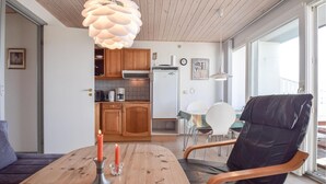 Een moderne keuken met houten kastjes, een witte koelkast en een eethoek met een houten tafel en stoelen.